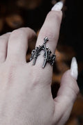 Silver ring with intricate design on a finger against a blurred background