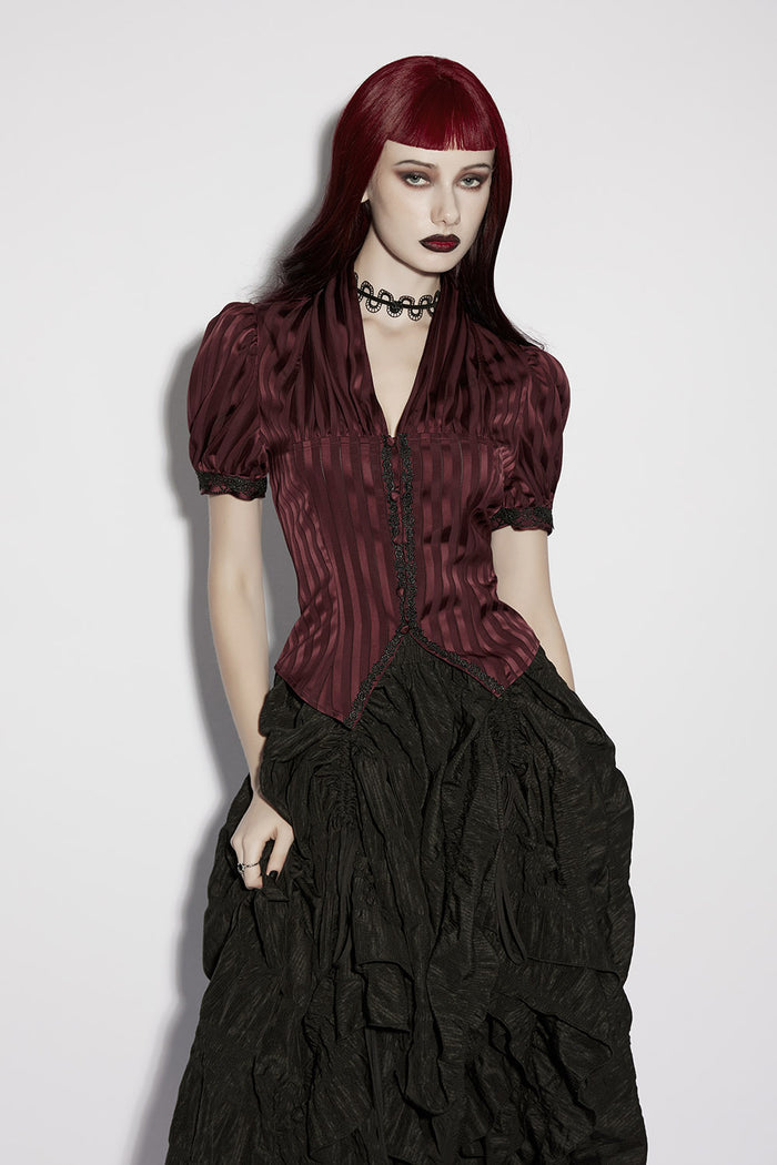 Woman wearing a gothic-style outfit with a maroon top and black ruffled skirt on a white background