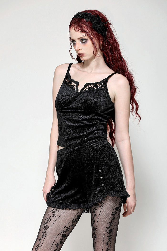 A woman wearing a black velvet tank top with adjustable shoulder straps and embroidered details.