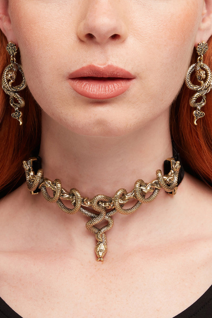 Gold snake necklace and earrings on a person with red hair.