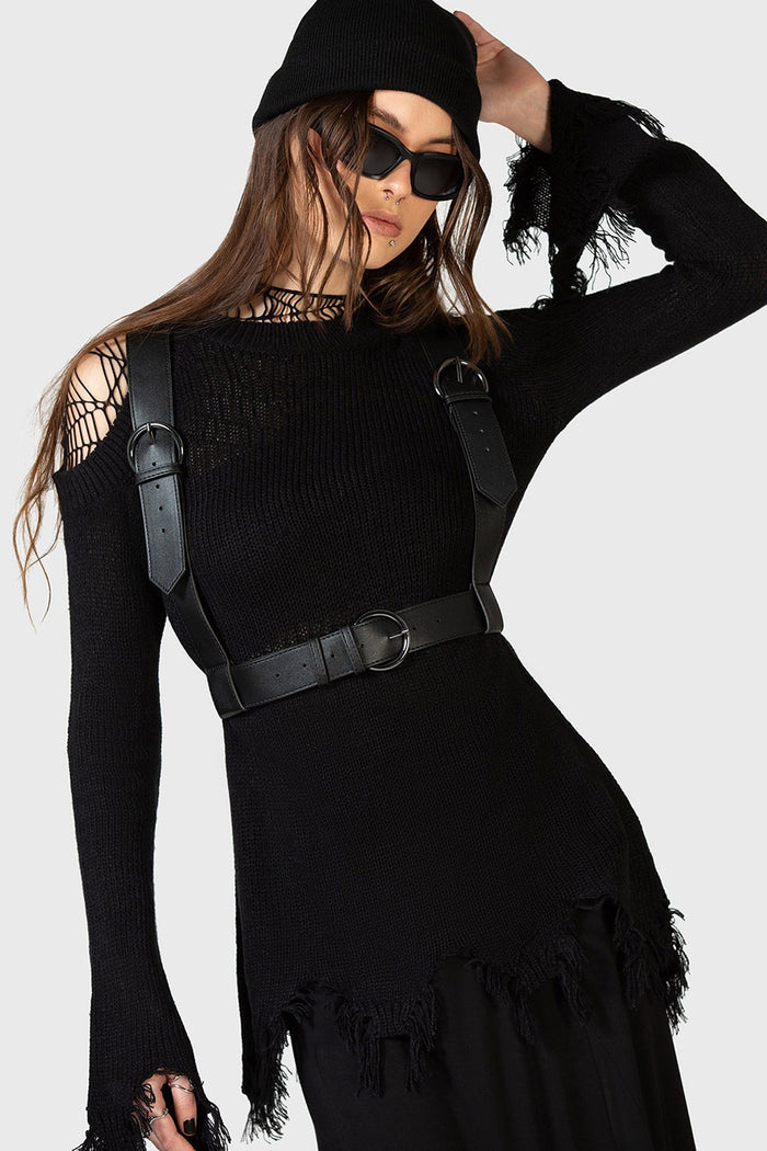 Woman wearing a black outfit with a gothic suspender harness on a white background