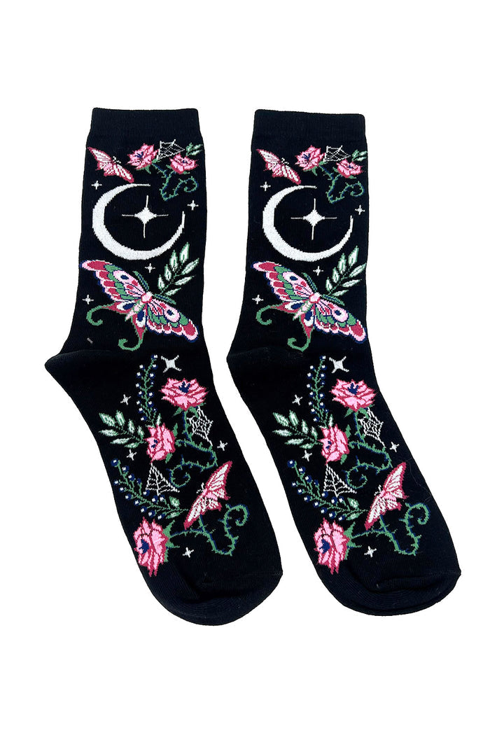 Black socks with pink flowers, green leaves, and white moons on a white background