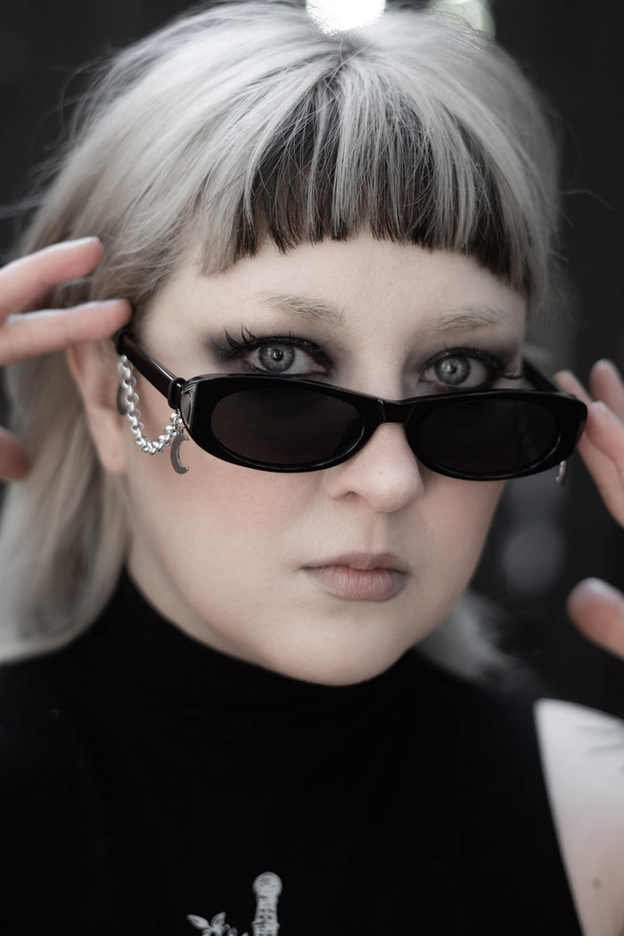 thin oval black sunglasses with crescent moon charms