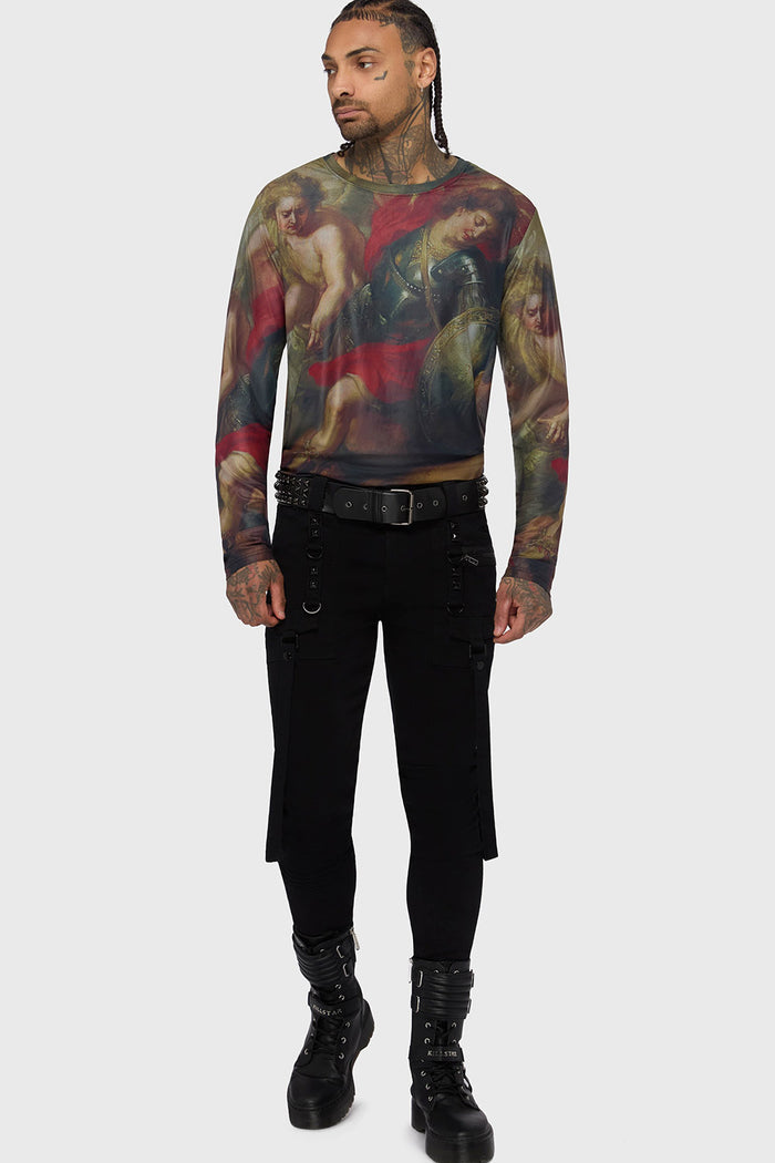 Person wearing a long-sleeve shirt with artistic design and black pants and a pyramid stud belt on a white background
