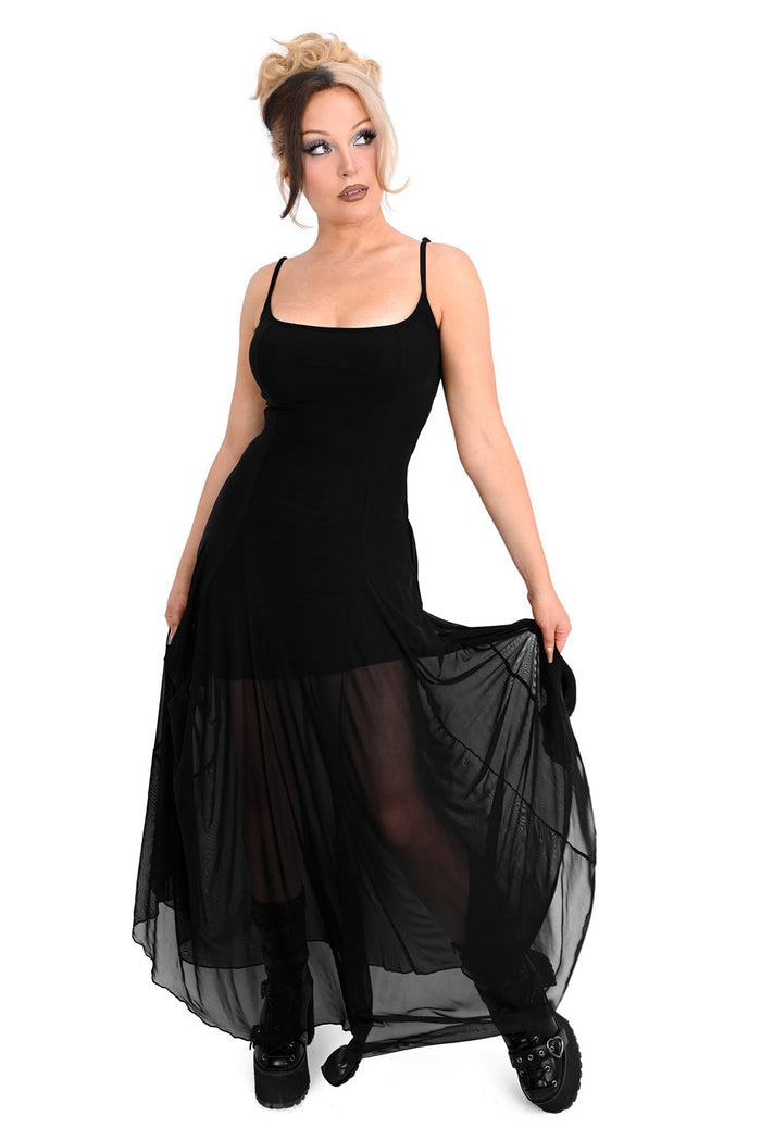 Woman wearing a black dress with sheer overlay on a white background