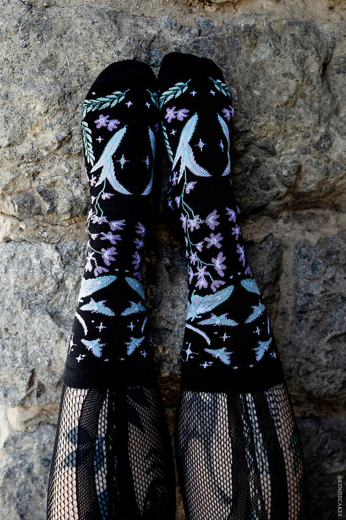 dark cottagecore knitted socks featuring moons, moths, and flowers