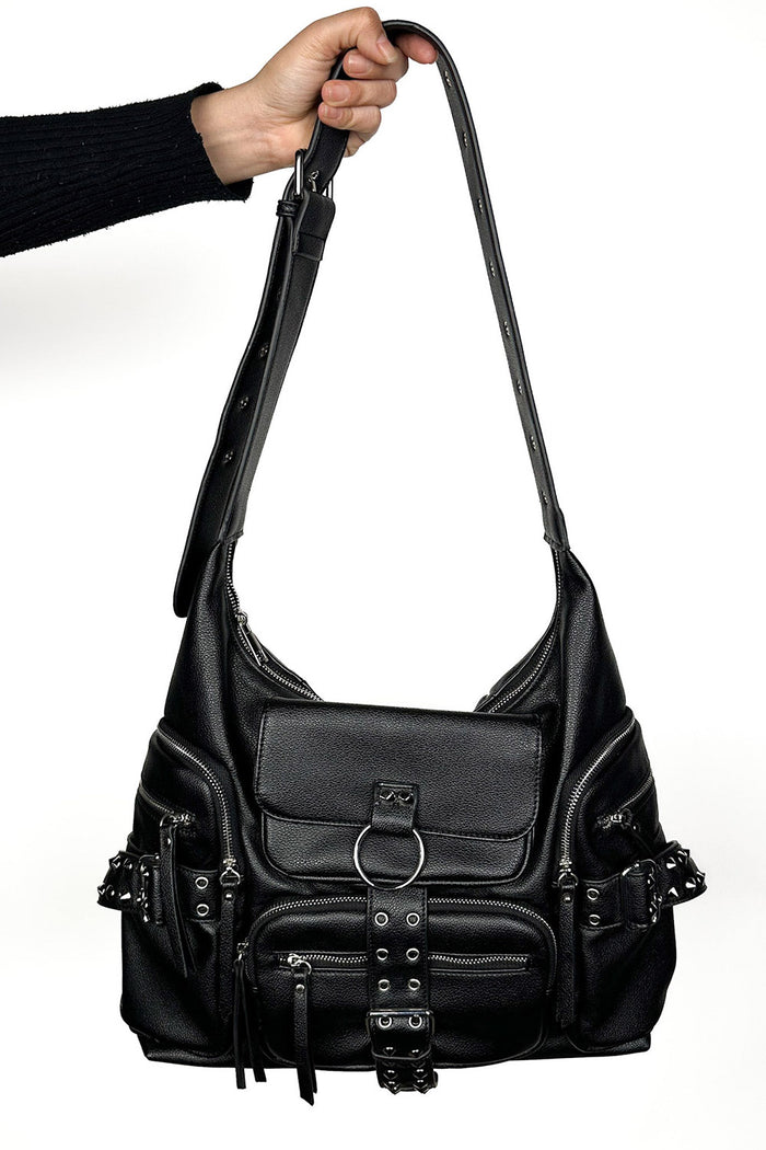 Black leather punk handbag held by a person on a white background